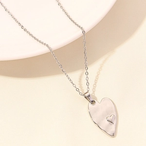 Macro view of silver hammered heart pendant and irregular stainless steel necklace charm