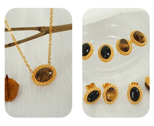 Detail of vintage gold necklace and tiger eye stud earrings set on white fabric