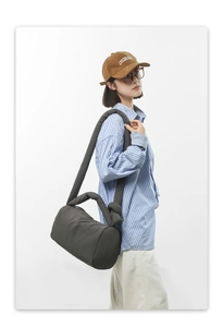 Detail of gray padded nylon crossbody bag with wide shoulder strap and side knot detail