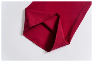 Detailed macro view of four-needle six-thread stitching on burgundy flared pants