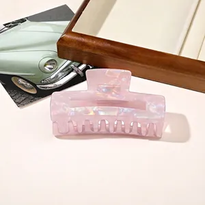 Macro view of square pearlescent hair claw clip with purple shell texture on wooden tray