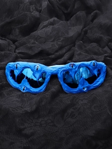 Gothic monster sunglasses with blue resin frames and eye details on black lace background