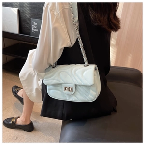 Close-up of light blue quilted PU leather bag with metal chain strap and twist lock