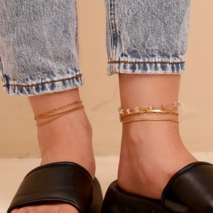 Detail of 18K gold-plated layered anklet set with paperclip, snake, and beaded chains