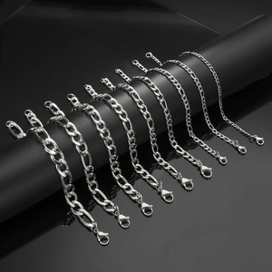 Macro detail of various thicknesses of silver Figaro chains with lobster clasps on black display