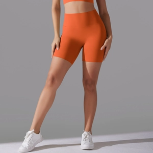 Detail view of bright orange high-waisted seamless yoga shorts showing fabric elasticity