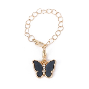 Détail d'une chaîne dorée avec pendentif papillon noir orné de strass blancs brillants