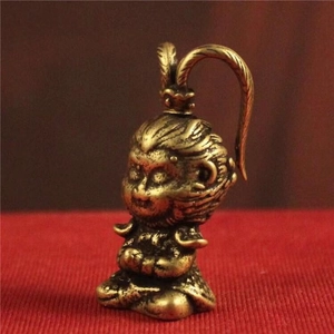 Detailed macro view of a brass Monkey King figurine seated on textured red fabric