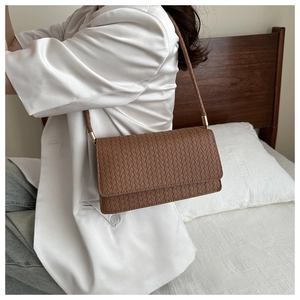 Detail of brown woven faux leather shoulder bag with gold metal buckle and smooth texture