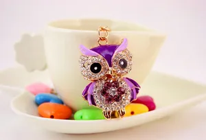 Macro shot of purple owl keychain with crystals and enamel on a white heart plate