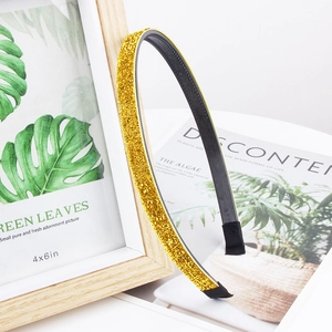 Detail of a golden glitter headband showing non-slip lining and shimmering texture
