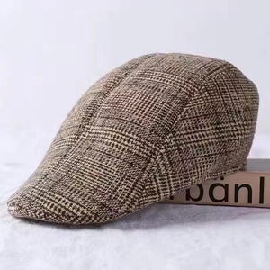 Detail of a brown plaid flat cap with thick wool texture for autumn and winter warmth