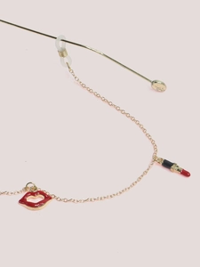Close-up of golden eyewear chain featuring red lips and black lipstick charms