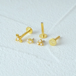 Macro view of gold 925 silver flat back studs with cross and clover crystal charms