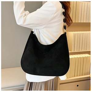 Detail of black suede crescent shoulder bag with unique gold and black chain strap