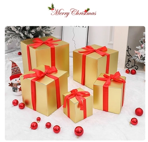 Set of five gold Christmas gift boxes with red satin bows in a festive winter scene