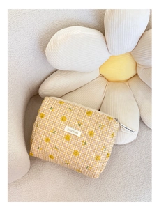 Détail macro d'une pochette matelassée à carreaux jaunes avec smiley et motifs floraux