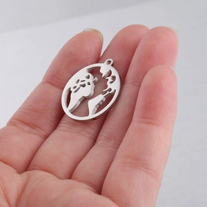 Close-up of silver world map cutout pendant in hand showing actual 20x22.3mm size