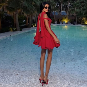 Close-up of red off-shoulder mini dress with elegant back ribbons by a pool