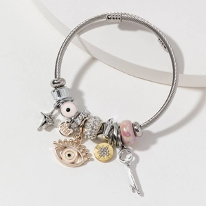 Silver woven bracelet with blue eye, crown, and key charms featuring crystal accents