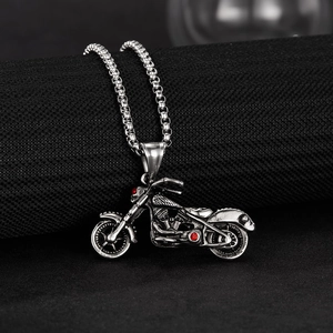 Détail macro du pendentif moto vintage avec strass rouges sur chaîne en acier inoxydable