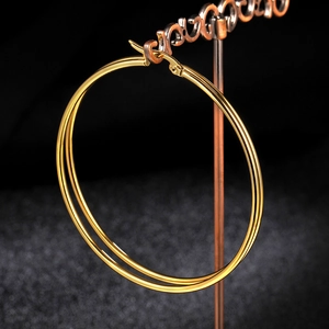 Macro shot of large golden stainless steel hoop earrings with glossy mirror finish