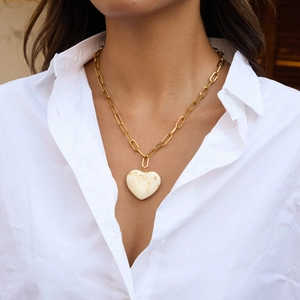 Λεπτομέρεια χρυσού κολιέ με συνδετήρες και μαρμάρινο μενταγιόν καρδιά σε μοντέλο
