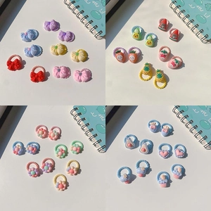 Close-up of colorful children's hair ties with resin fruit and floral charms on white background
