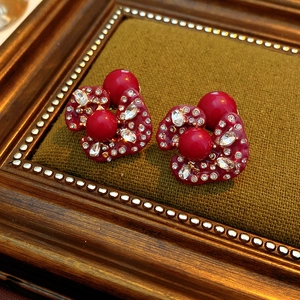 Macro detail of vintage red gemstone earrings with gold frame on green velvet background