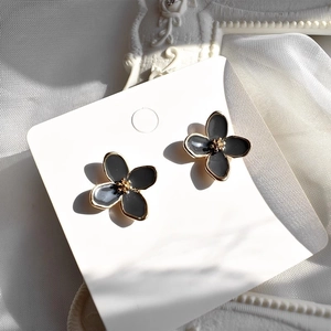 Macro view of black enamel flower earrings with elegant gold-plated floral petals