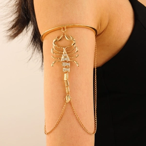 Detailansicht einer goldenen Skorpion-Armmanschette mit Strasssteinen am Frauenarm