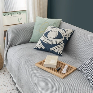Nordic style gray knitted sofa cover blanket draped over a couch in a cozy living room