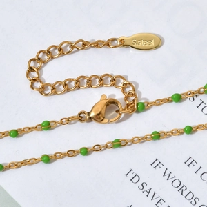 Macro detail of gold stainless steel necklace with green enamel beads and lobster clasp