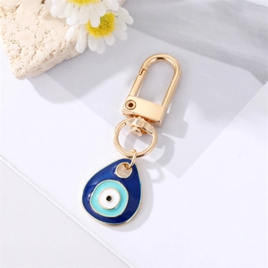 Blue Evil Eye teardrop keychain with golden metal ring on white marble surface