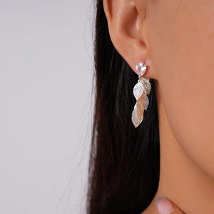 Gros plan de boucles d'oreilles feuilles évidées avec zircon goutte sur un modèle