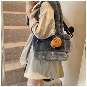 Close-up of gray quilted plush shoulder bag with brown bear charm on beige coat