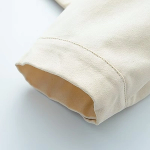 Detail showing high-quality stitching on beige cotton twill sleeve cuff of a jacket