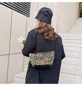 Close-up of sparkling sequin crossbody bag with chain strap and premium black leather base