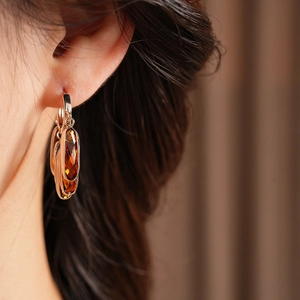Gros plan de boucles d'oreilles vintage en verre ambré avec finition dorée sur modèle