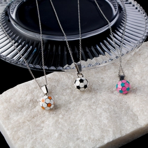 Three football pendant necklaces in orange, black, and blue on stone stands