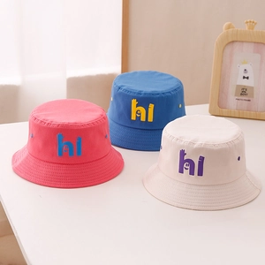 Détail de chapeaux bobs enfants en rose, bleu et beige avec motif hi rigolo