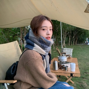 Outdoor shot of a soft blue plaid cashmere scarf worn by a woman at a campsite