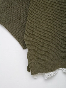 Detailed close-up of olive green knit fabric with white hollow lace patchwork hem