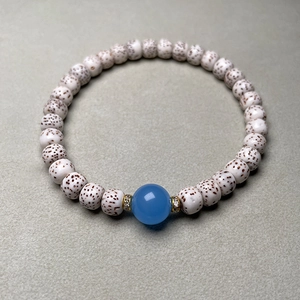 Macro shot of Star Moon Bodhi beads with a blue agate centerpiece and golden spacers