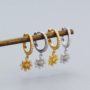 Detail of silver and gold eight-pointed star huggie hoop earrings with sparkling zircons