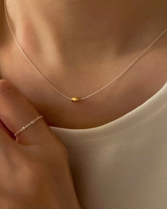 Collar minimalista de plata con colgante de haba dorada usado por una modelo