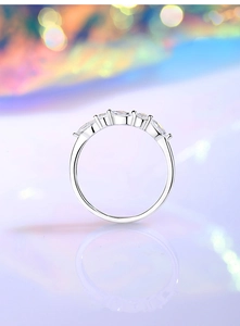 Detail of silver ring with marquise-cut zircons and claw setting on reflective surface