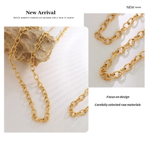 Close-up of golden geometric chain necklace with textured links on minimalist stone
