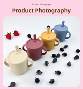 Detail of four Morandi-colored silicone baby training cups with handles and straws