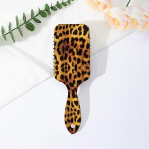 Detail view of leopard print hairbrush with hanging hole on a white fabric background